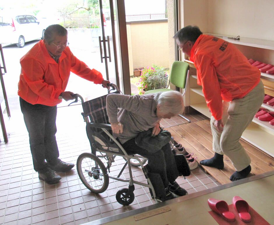 蛍光オレンジのスタッフジャンパーを着用して自治会での防災訓練中の写真