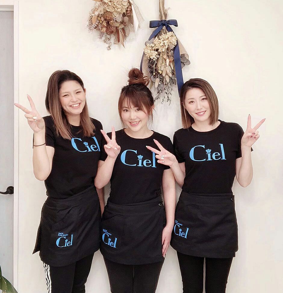 ネイルサロン様での実際のユニフォームとしての採用写真を送っていただけました♪ <br>全身、黒コーディネイトの中の水色のロゴマークが印象的です！